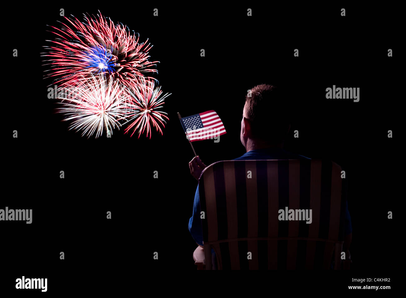 Ein Mann wacht ein Feuerwerk während winken eine amerikanische Flagge zeigen. Stockfoto