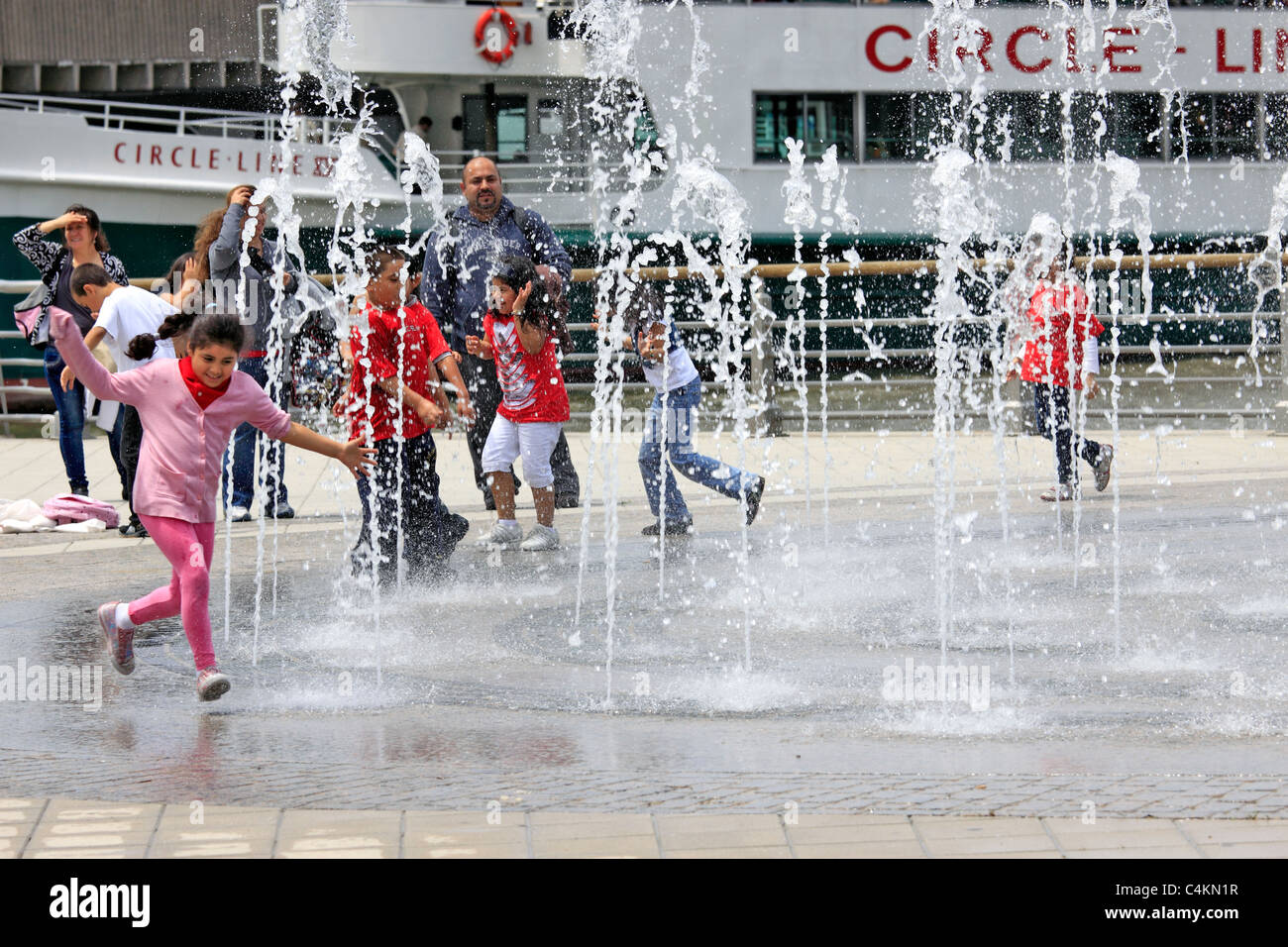 Kinder spielen im Wasser Sprinkler Circle Line Pier Manhattan New York City Stockfoto