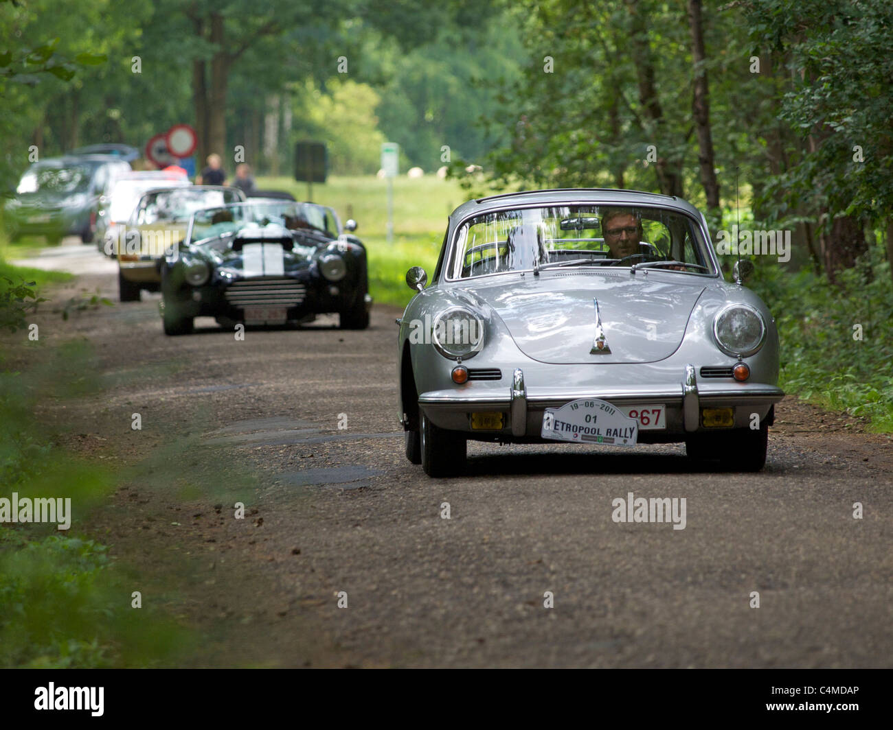 Oldtimer-Rallye in der belgischen Landschaft, Porsche 356 vor gefolgt von AC Cobra und einen klassischen 911 Porsche. Stockfoto
