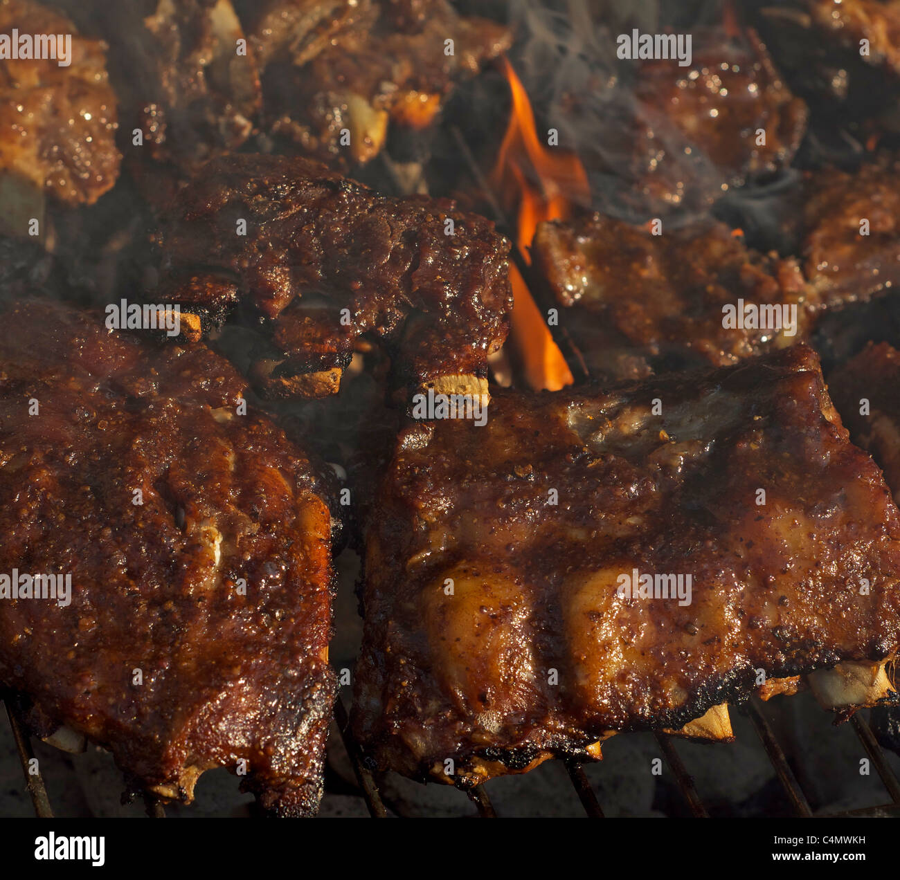 Schweinerippchen, Kochen auf einem Bbq-Grill mit Flammen und Rauch Stockfoto