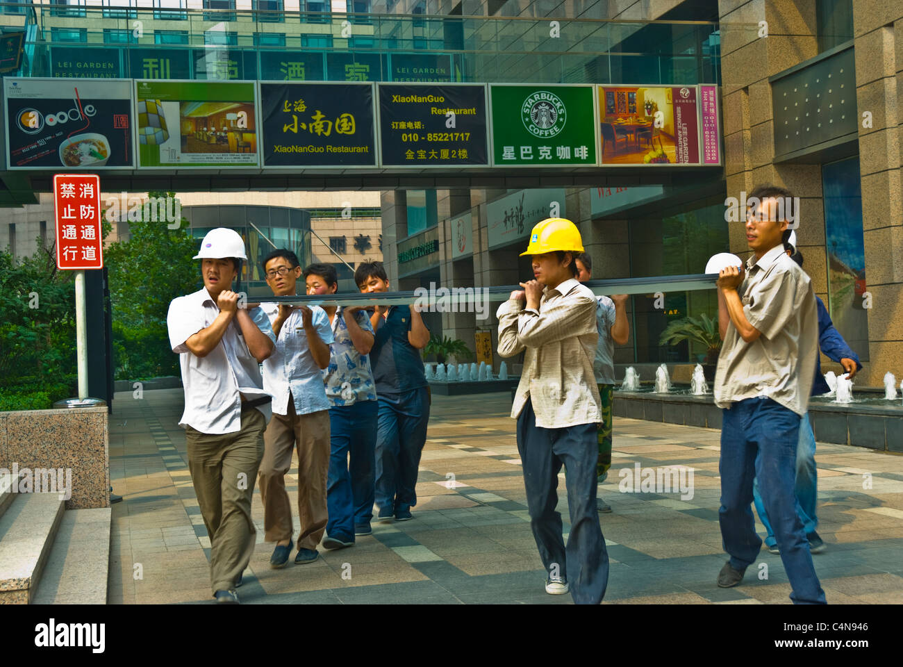 Peking, China, Gruppe chinesischer Arbeiter, die schwere Glasplatten auf der Baustelle im Stadtzentrum transportieren Stockfoto