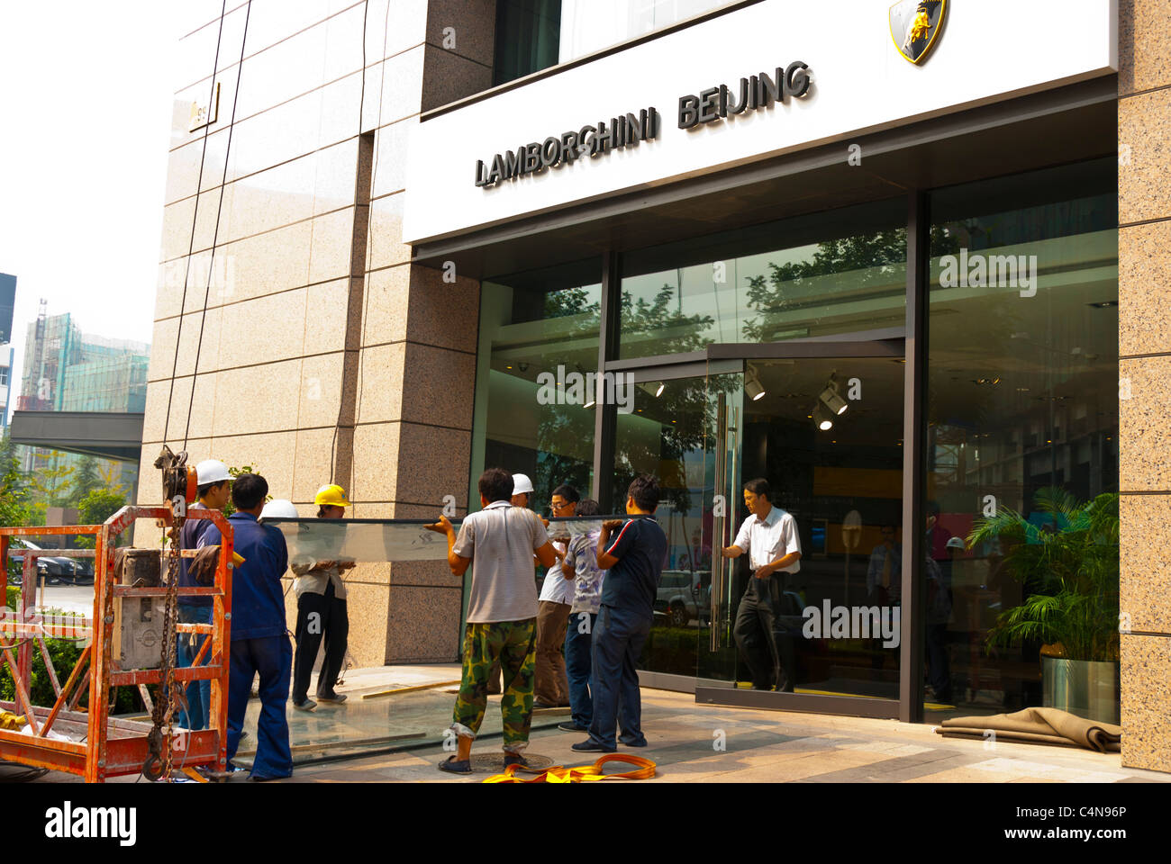 Peking, China, Gruppe chinesischer Arbeiter, die schwere Glasplatten auf der Baustelle im Stadtzentrum, Eingang des Lamborghini-Gebäudes tragen Stockfoto