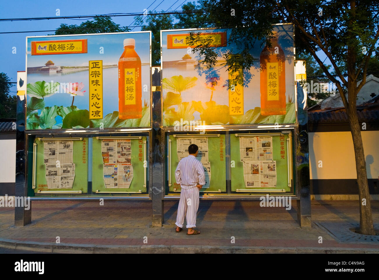 Peking, China, Mann, der Lokalzeitung auf der Plakatwand auf der Straße liest, Außenwerbung, chinesische Altstadtstraße Stockfoto