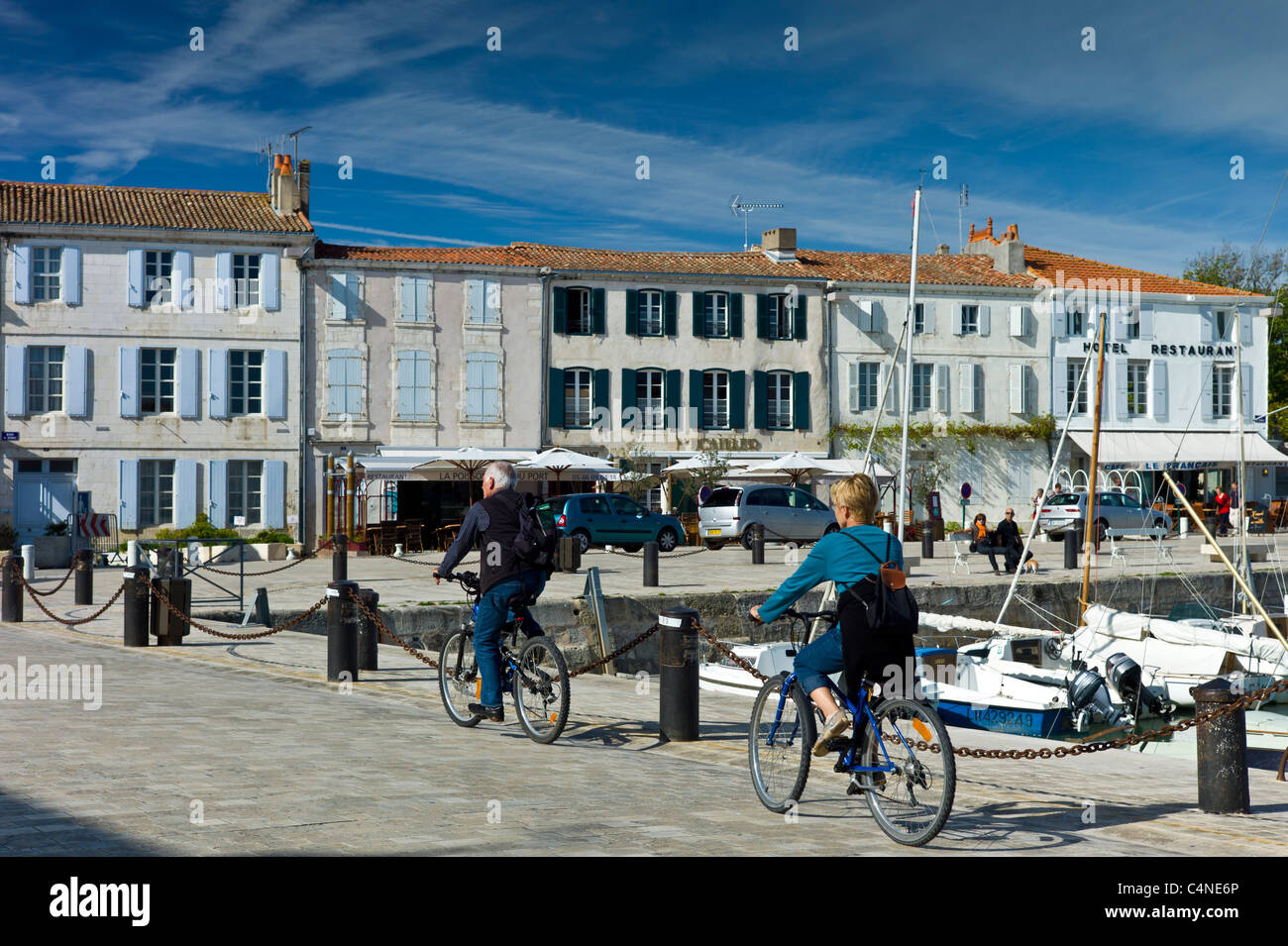 Touristen, die Radfahren entlang des Hafens am Quai de Senac in La Flotte, Ile de Ré, Frankreich Stockfoto