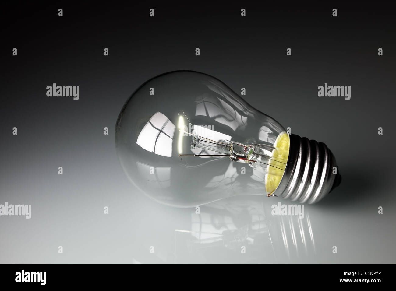 Glühbirne auf Grauglas Hintergrund mit Reflexion Stockfoto