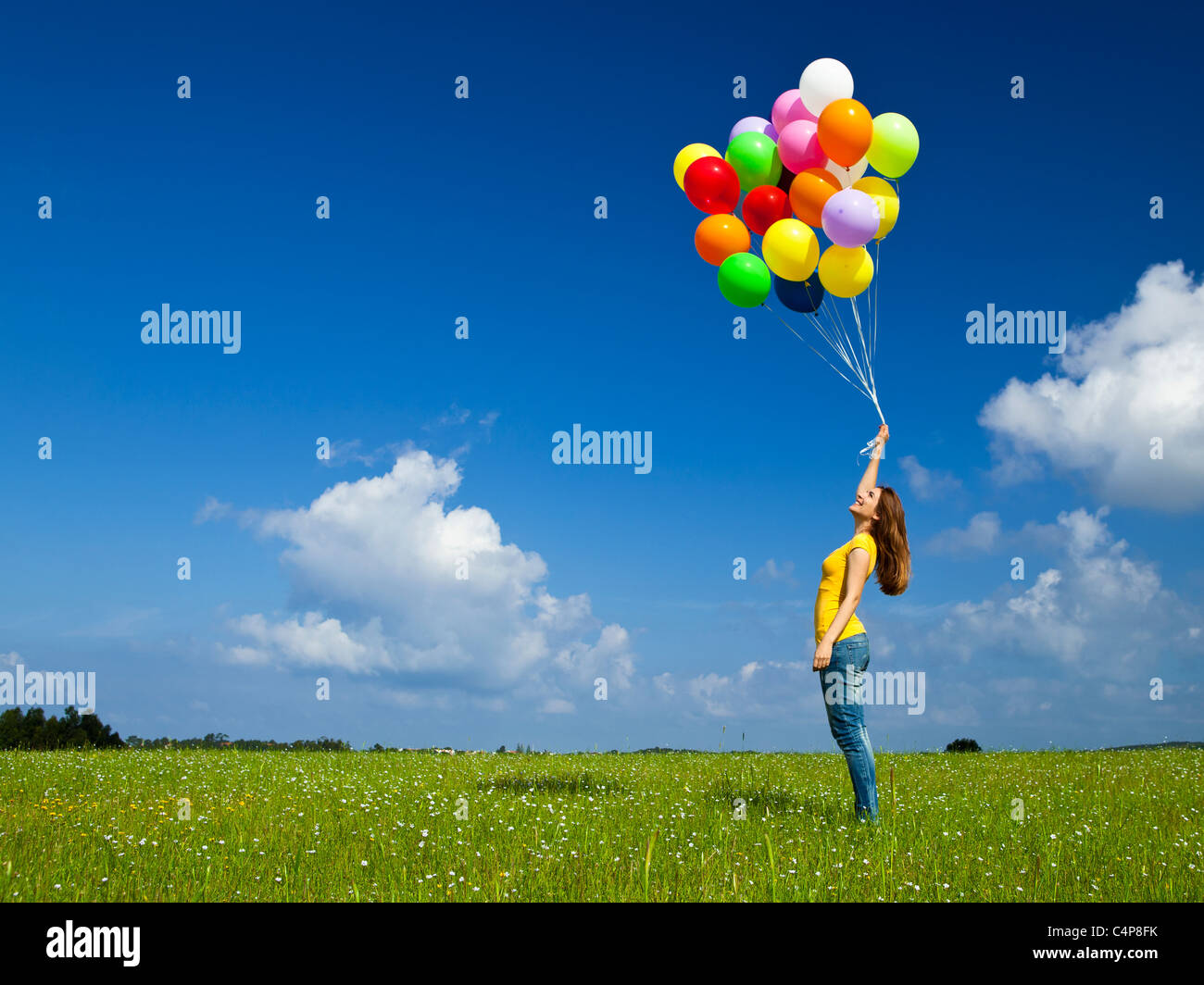 Glückliche junge Frau mit bunten Luftballons auf der grünen Wiese Stockfoto