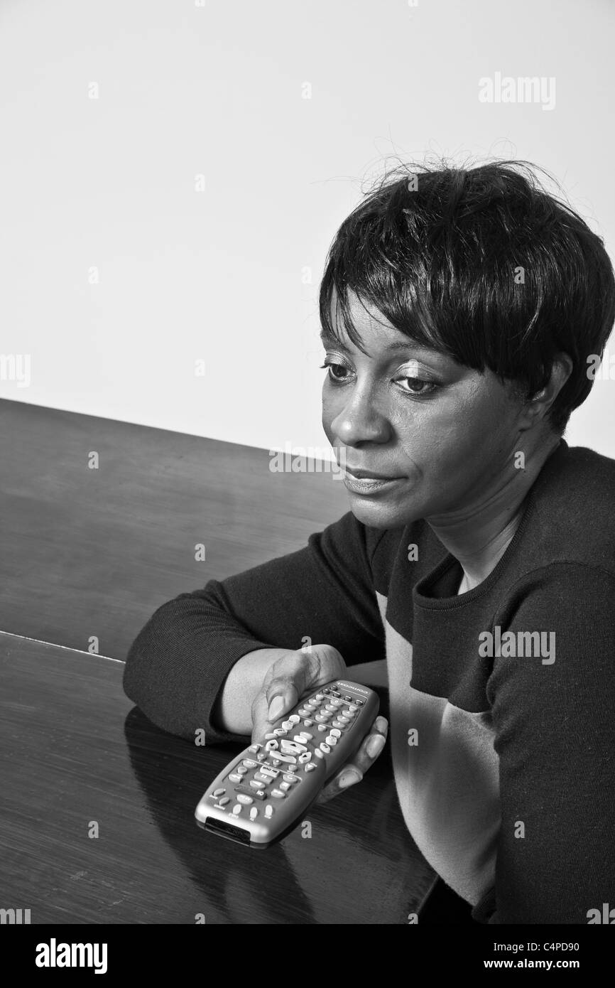 Schwarze Frau mit einer TV-Fernbedienung Stockfoto