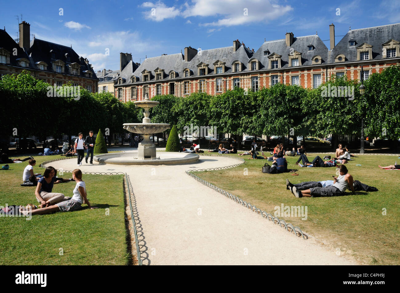 Leute sitzen in der Sonne in Place des Vosges in Paris Stockfoto