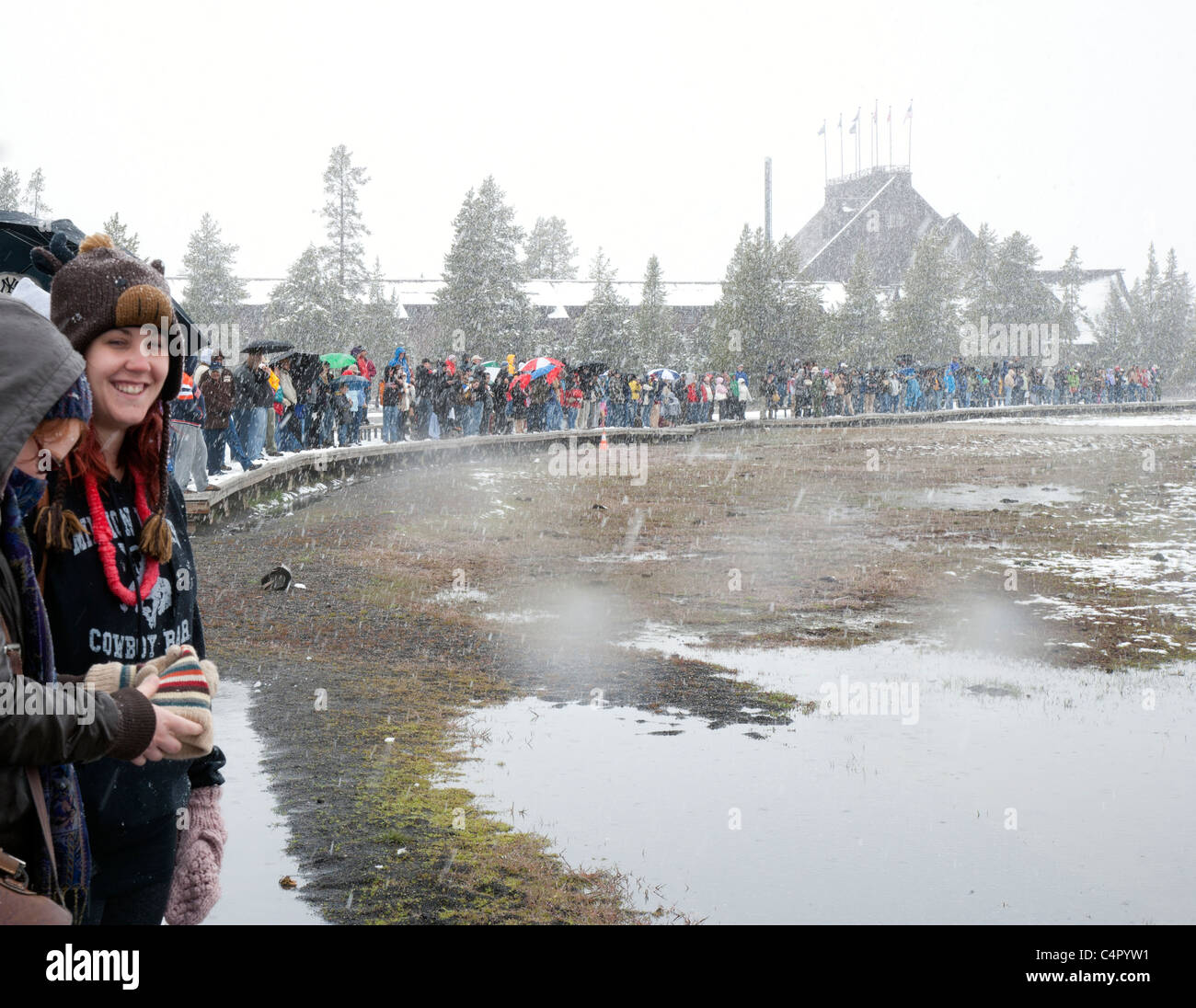 Eine Menge von Menschen wartet im Schneesturm auf den Ausbruch des Old Faithful Geysirs Stockfoto