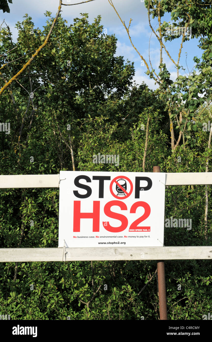 Stoppschild HS2 High Speed Rail 2 befestigt an einem Holzzaun mit Bäumen und blauen Himmel im Hintergrund Stockfoto