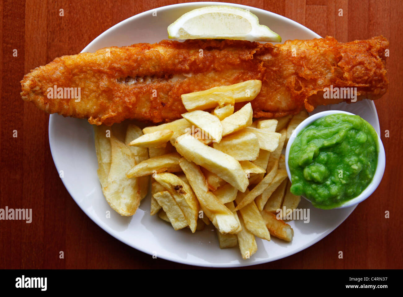 Ein Teller mit Fish &amp; Chips ist mit Erbsenpüree und einen Keil von ...