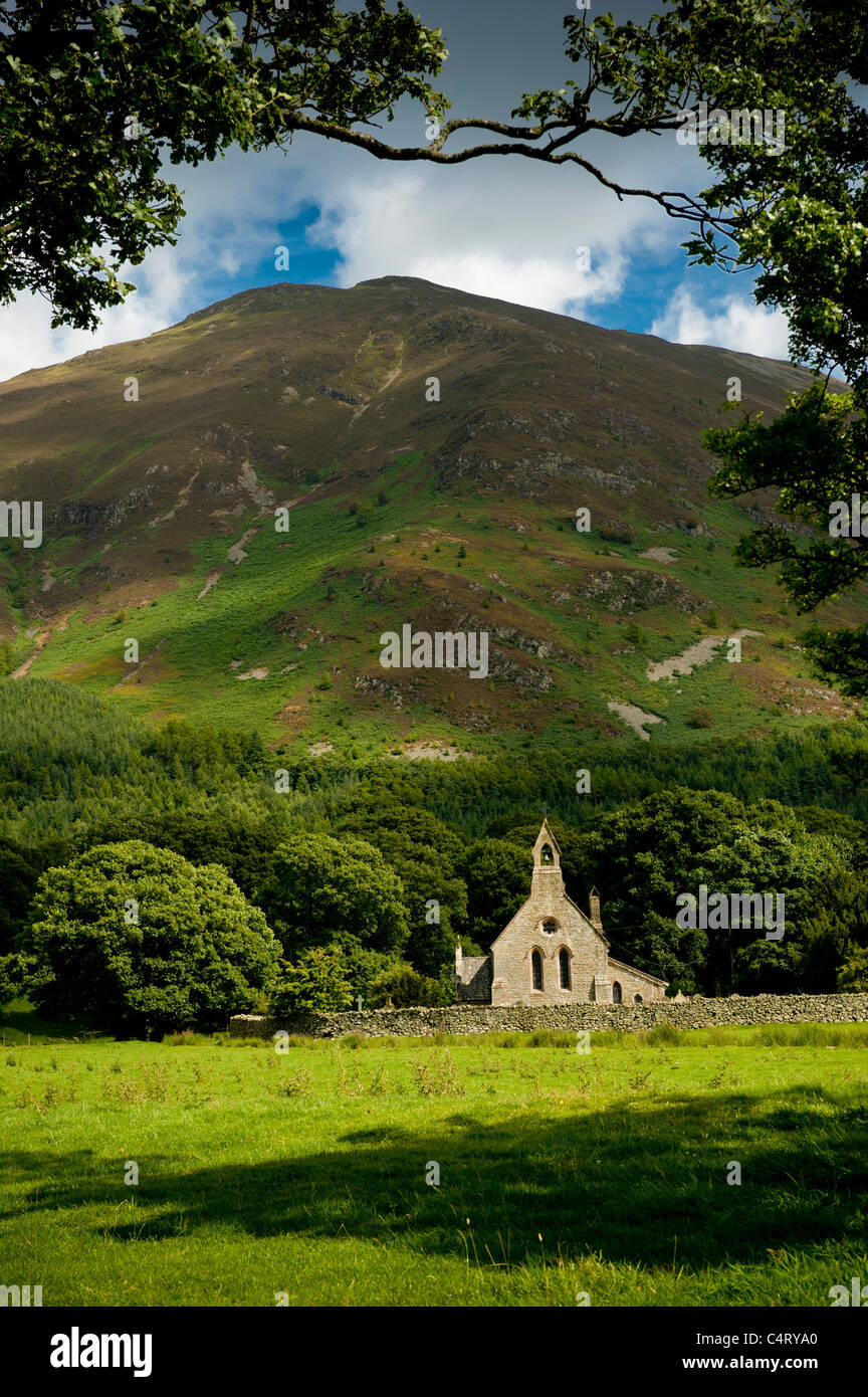 Die abgelegene Kirche St. Bega's in Bassenthwaite, eingerahmt von einem Baum mit Ullock Pike und Skiddaw. Cumbria UK Stockfoto