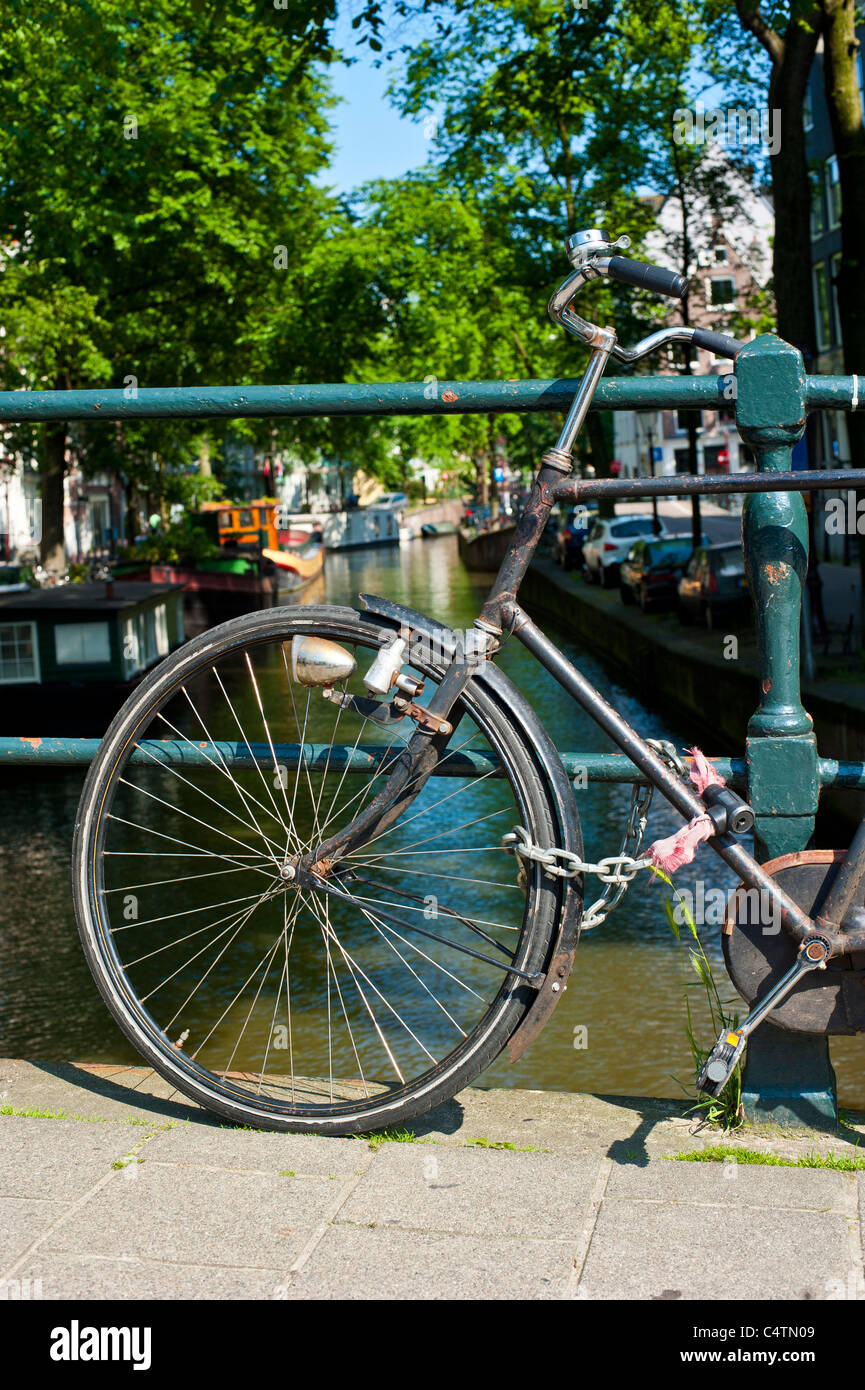 Fahrrad angekettet an einer Brücke über einen Kanal in Amsterdam Stockfoto