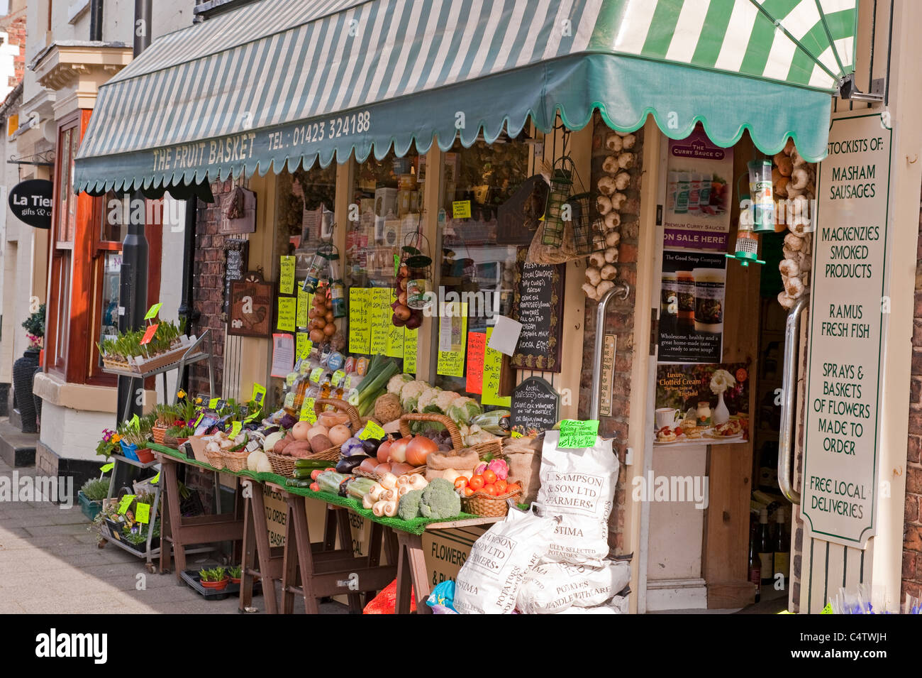 Gemüsehändler & lokale unabhängige High Street Shop (Obst & Gemüse Display & gestreifte Markise draußen) -The Fruit Basket, Boroughbridge, Yorkshire, UK. Stockfoto