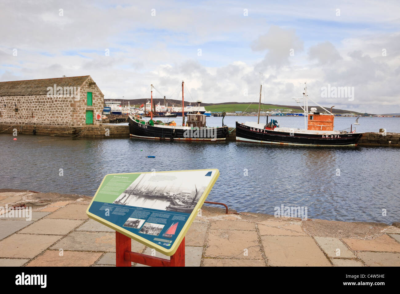 Lerwick, Shetland Islands, Schottland, UK, Europa. Hay es Dock mit Tourist-Info-Tafel und alte Boote in der Nähe des Museums Stockfoto