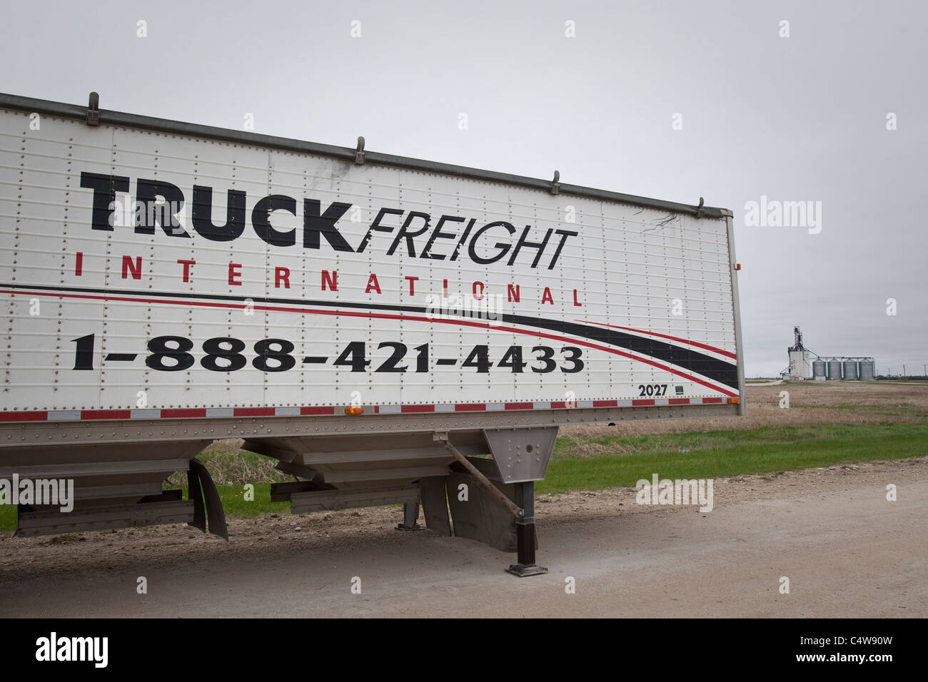 Ein LKW Fracht, die International Trailer zur geschleppte Körner ist durch ein Getreidesilo und Getreidesilos in der Nähe von Winnipeg abgebildet. Stockfoto