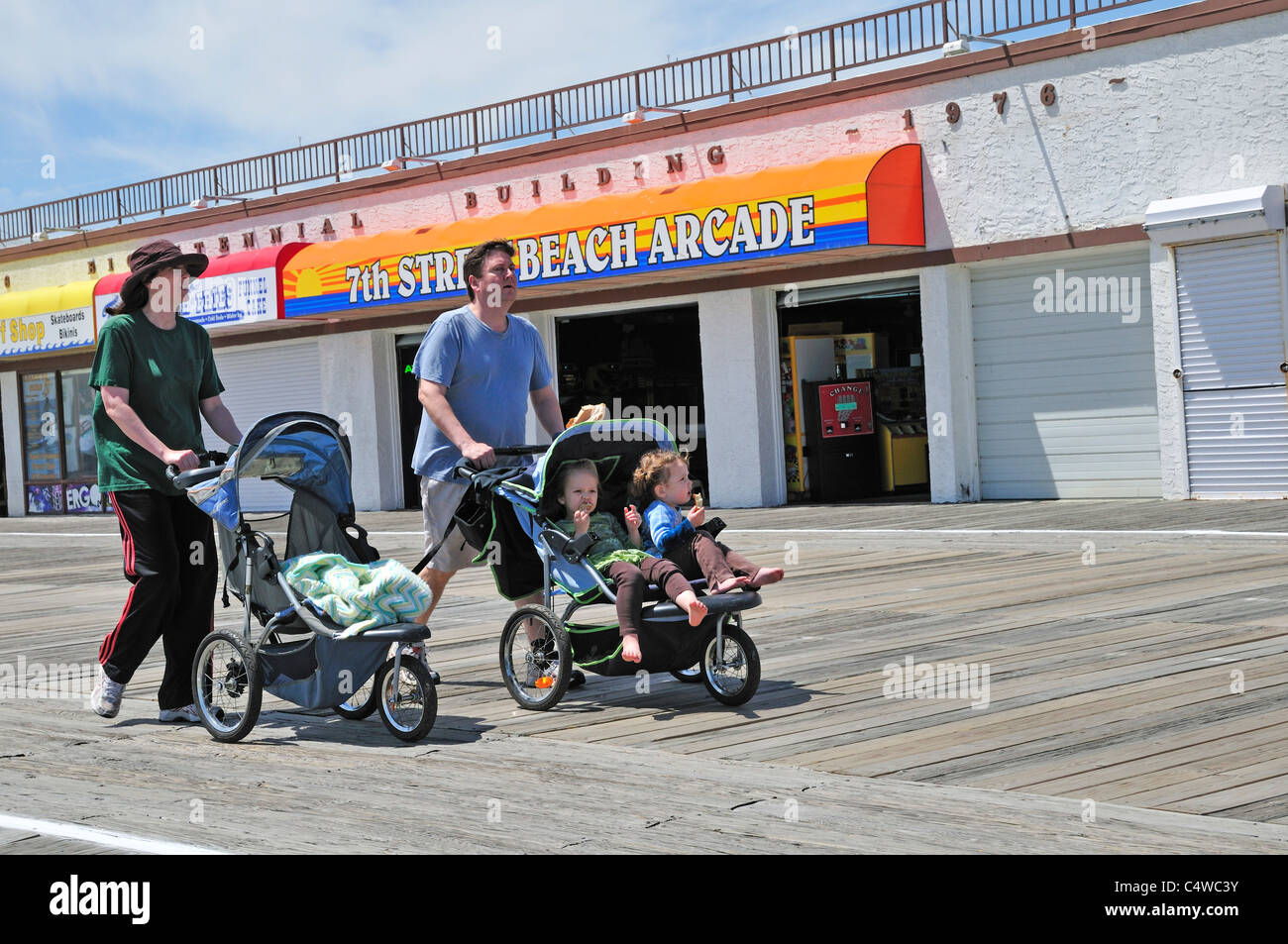 Ein Mann und eine Frau nehmen Kinder für eine Fahrt auf der Promenade in Ocean City, New Jersey Stockfoto
