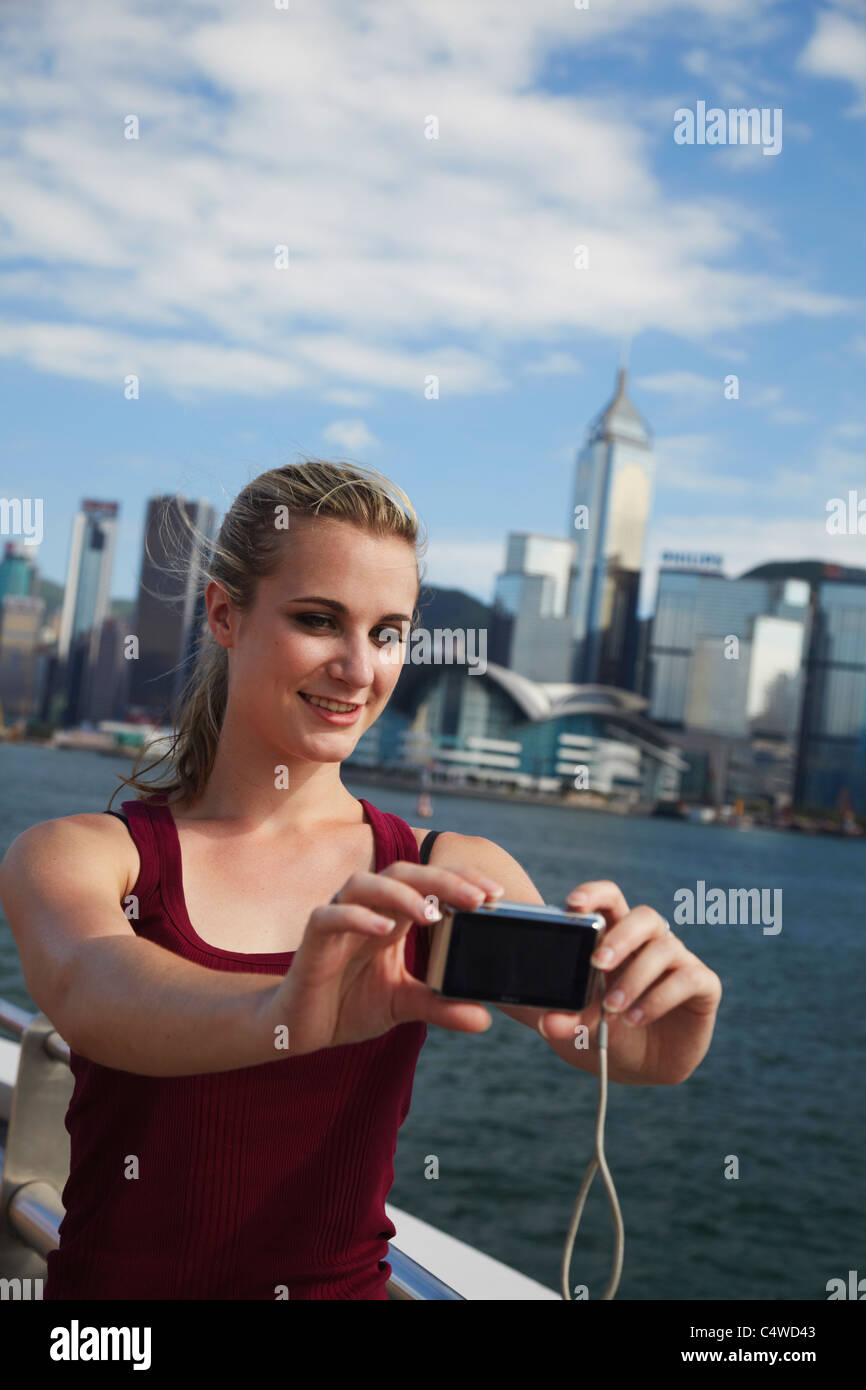 Frau nehmen Foto von sich selbst vor der Skyline von Hong Kong, Hong Kong, China Stockfoto