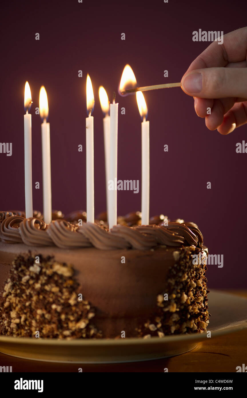 Studioaufnahme des Menschen zünden Kerzen auf Schokolade Geburtstagskuchen Stockfoto