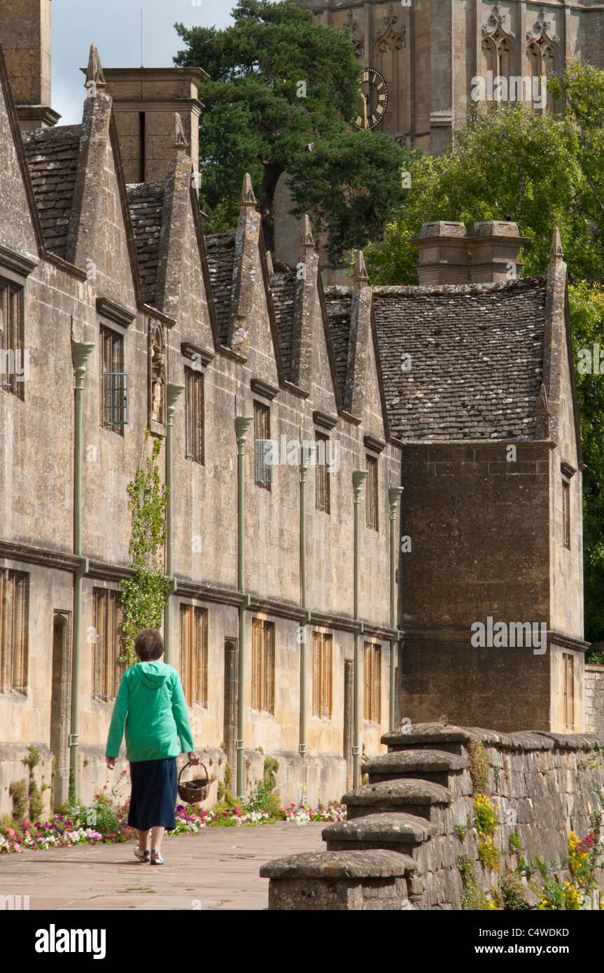 Eine Frau geht vorbei an Armenhäuser in der Nähe von St James Church, Chipping Campden in Worcestershire Cotswolds. UK Stockfoto