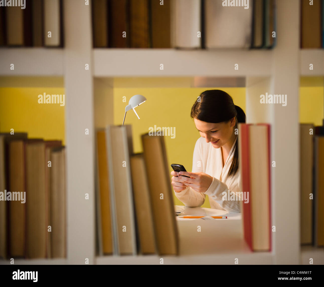 USA, New Jersey, Jersey City, junge Frau Textnachrichten in Bibliothek Stockfoto