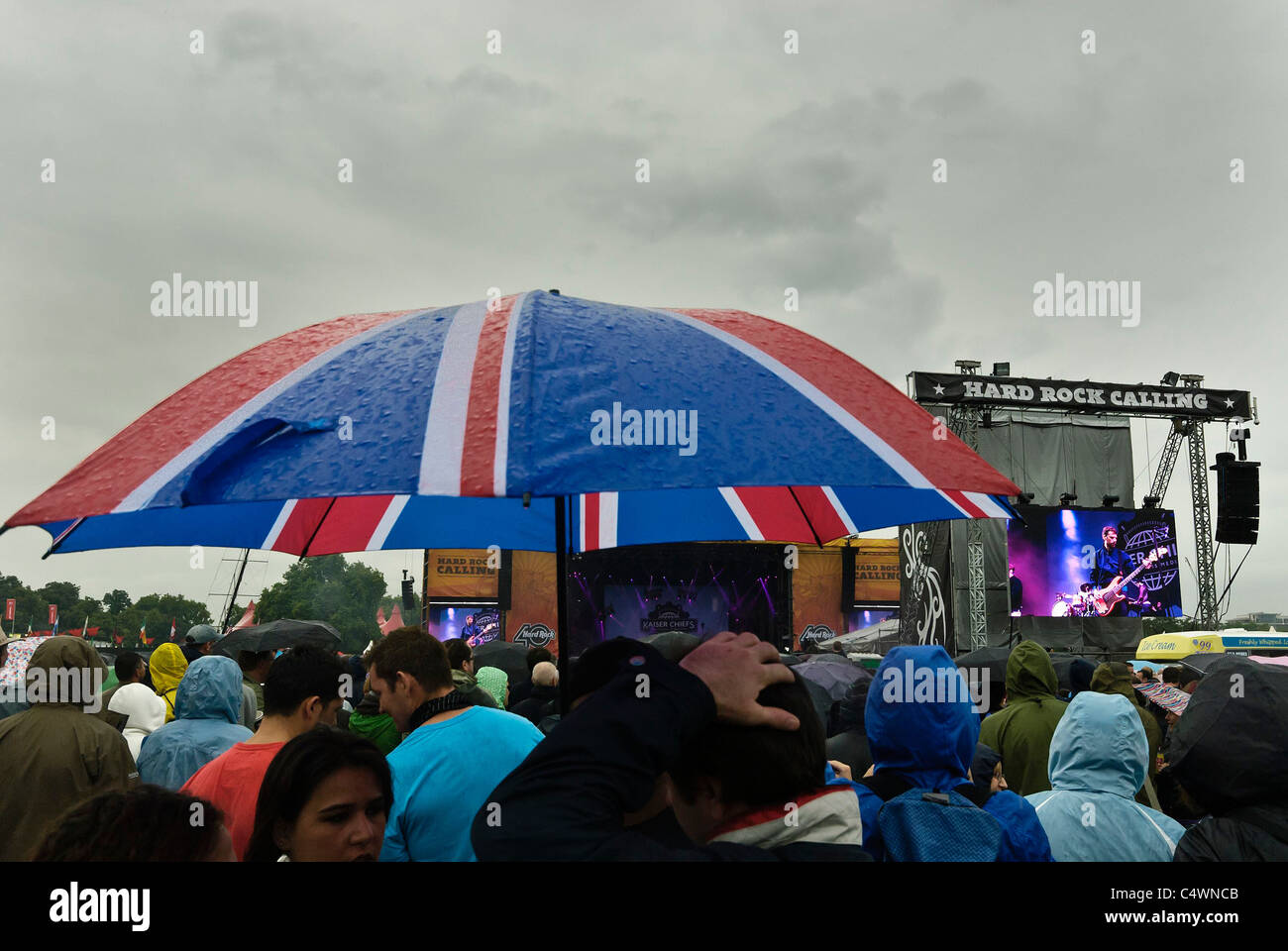 Zuschauern Schutz vor dem Regen beim Hard Rock Calling Music Festival, Hyde Park. Bild von Julie Edwards Stockfoto