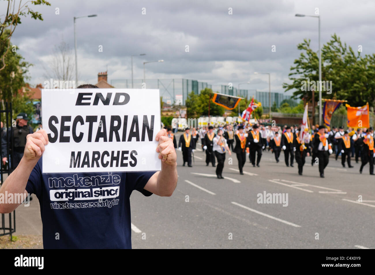 Mann hält Schild "Ende sektiererischen Märsche" als der Whiterock Oranier-Orden Parade verläuft friedlich ab. Belfast 25.06.2011 Stockfoto