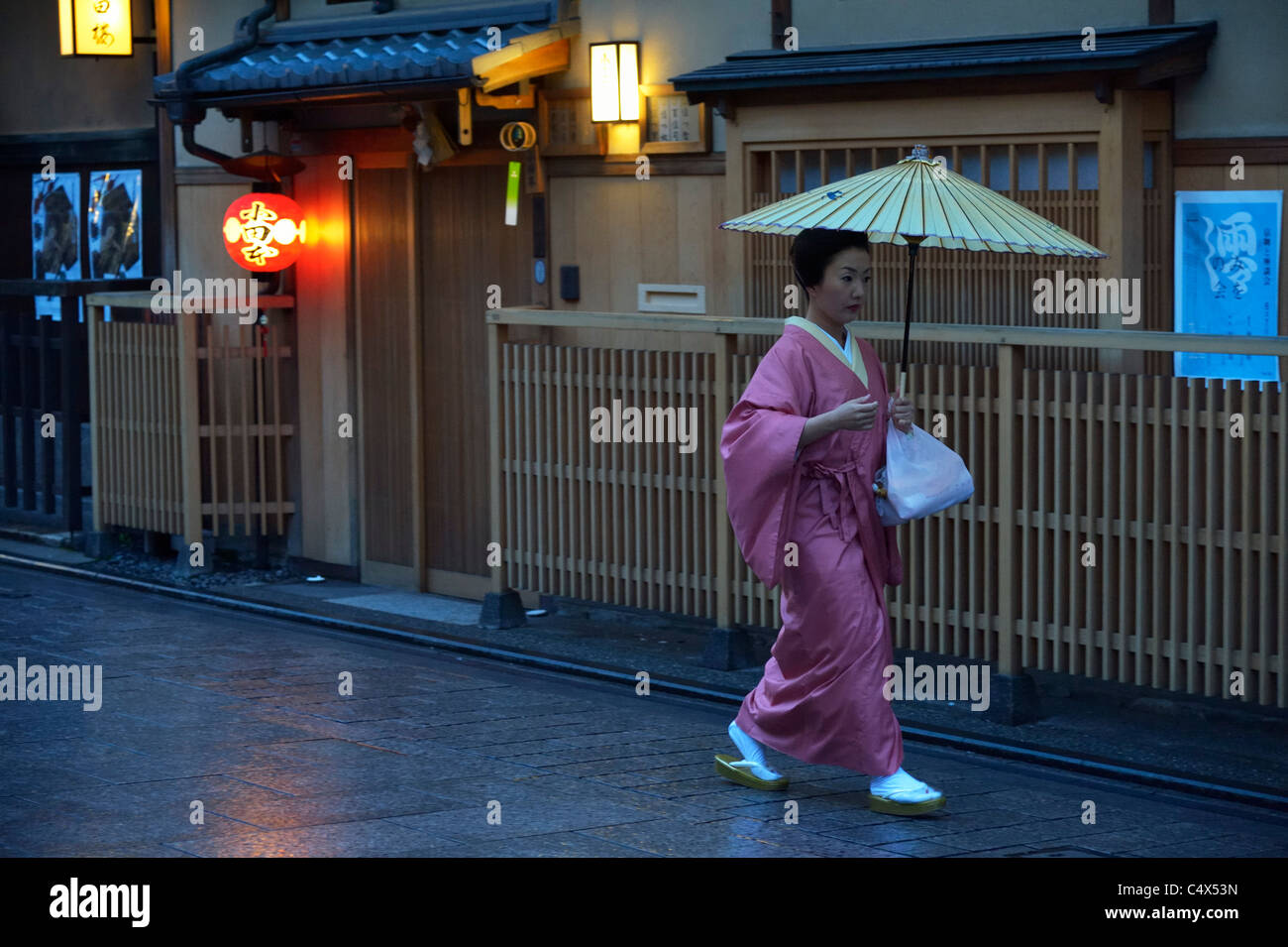 Eine japanische Geisha (Geiko) läuft entlang traditioneller Restaurants im historischen Gion Viertel, Kyoto, Japan JP Stockfoto