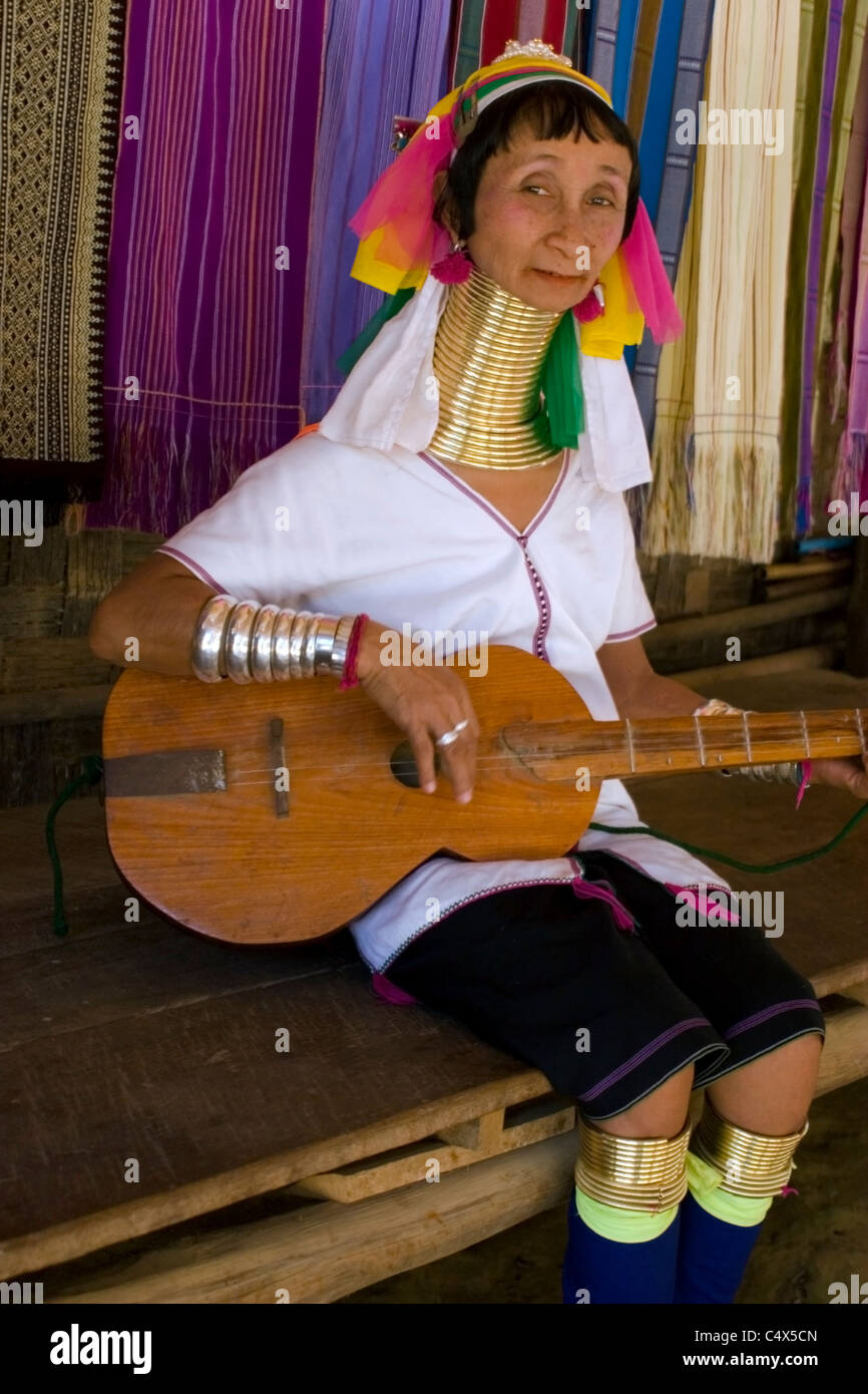 Karen Paduang Flüchtling Frau gold Ringe um den Hals tragen ist eine hölzerne Gitarrenspiel in einem Flüchtlingslager in Thailand. Stockfoto