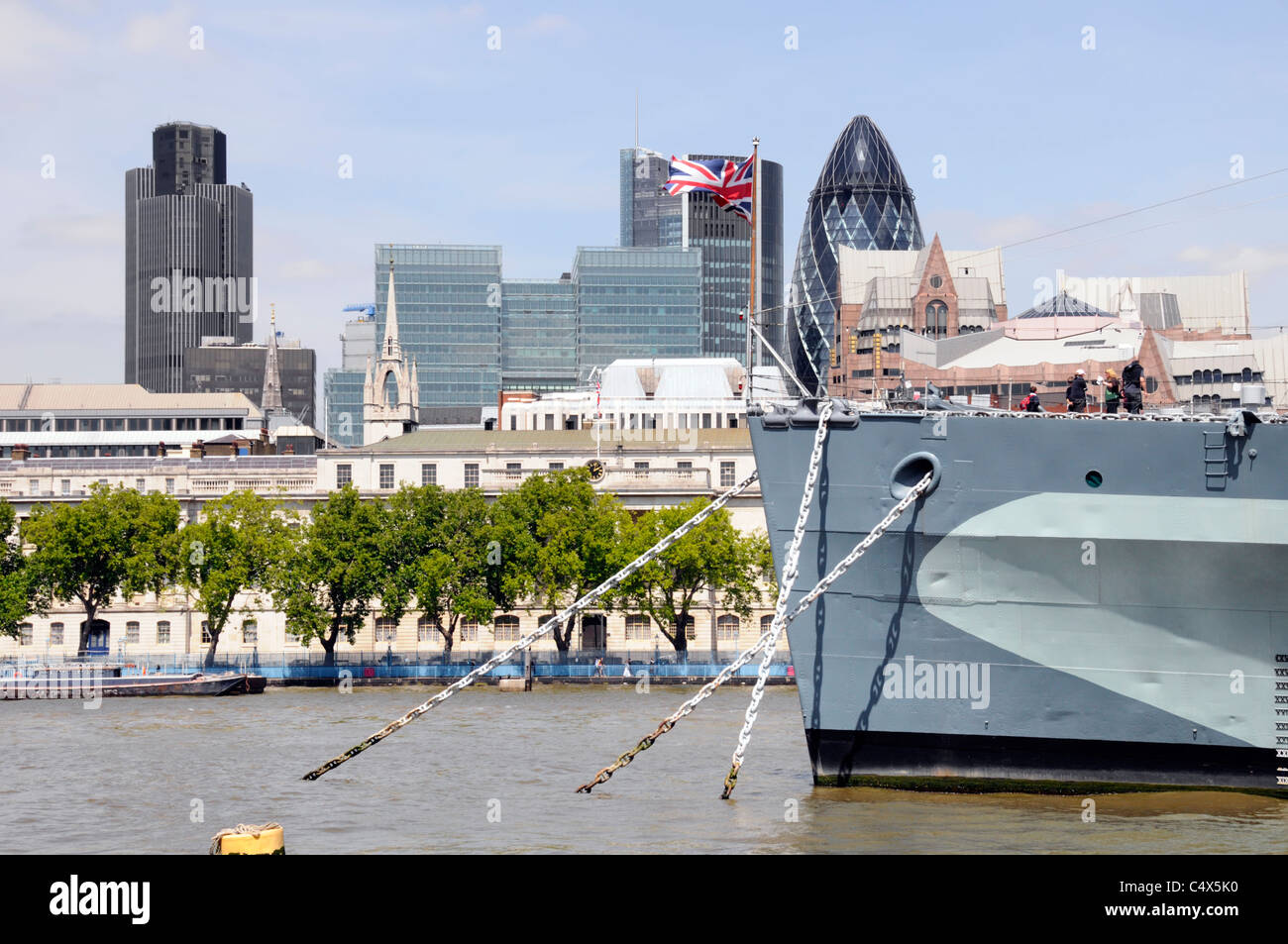 Union Jack, der auf dem Bogen des historischen Museumsschiffs "HMS Belfast" mit der Skyline der City of London von Wolkenkratzern fliegt, das Wahrzeichen der Geschäftsstelle, blockiert England Großbritannien Stockfoto