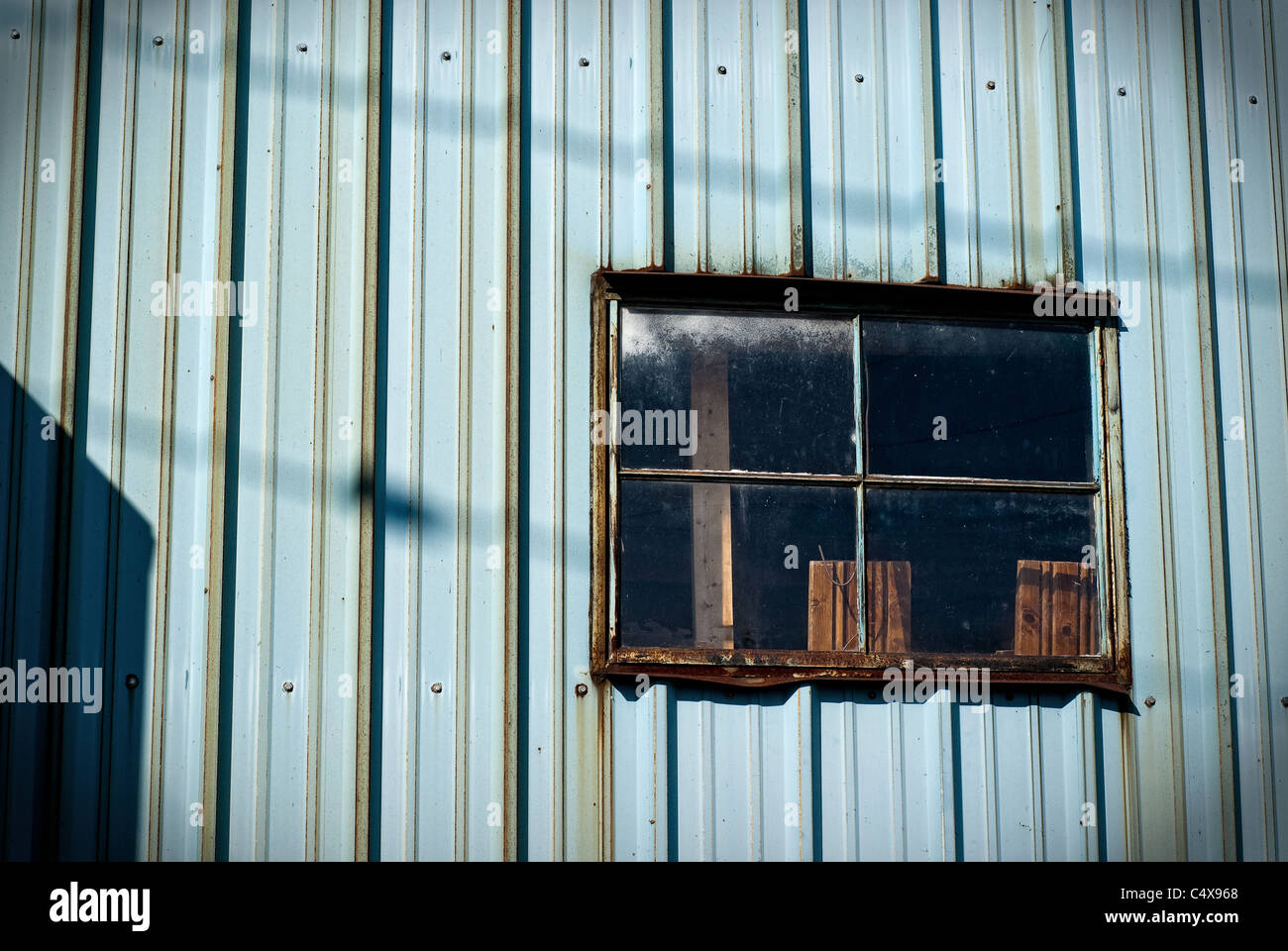 Einer alten, rostigen Metall Fenster auf eine blaue Wellpappe Zinn Wand. Stockfoto