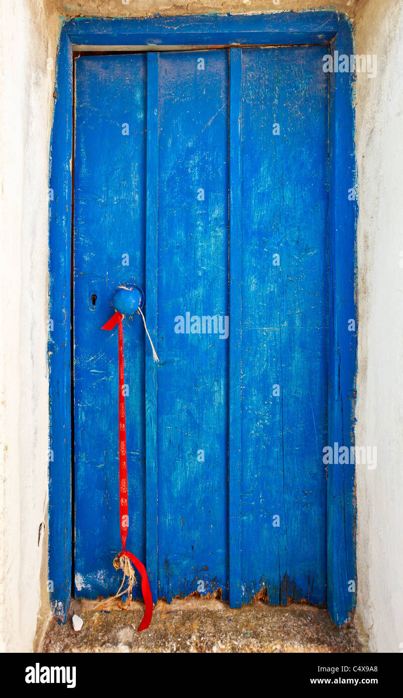 Nahaufnahme einer alten blauen Tür aus Griechenland mit einem roten Baumwoll-Gurt, Tinos, Griechenland Stockfoto