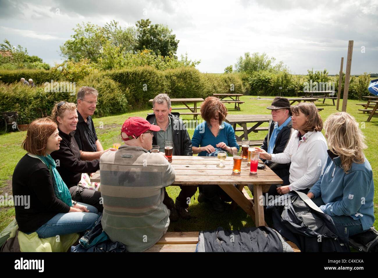 Eine Gruppe von Leuten, die draußen sitzen und im Biergarten des Jolly Sailor Pub, Orford, Suffolk, Großbritannien, trinken Stockfoto