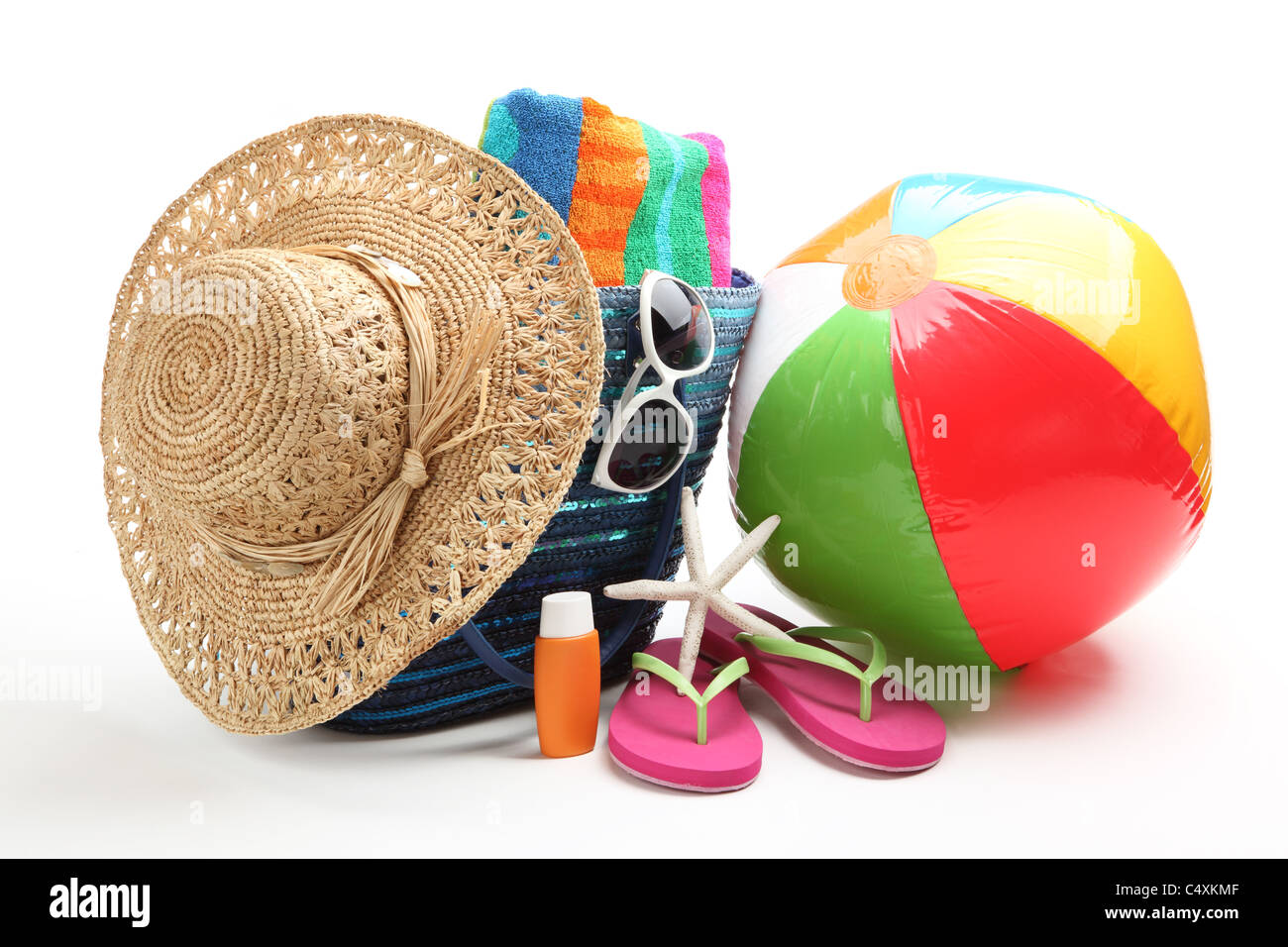 Strandzubehör mit Strohhut, Handtuch, Flip Flops, Sonnencreme, Wasserball und Sonnenbrillen. Stockfoto