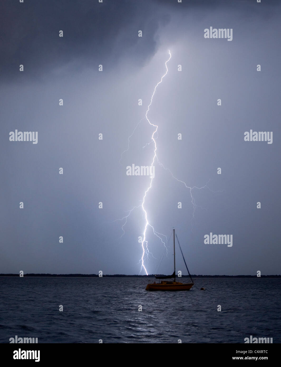 Ein Blitzeinschlag in der Nähe von einem festgemachten Segelboot. Stockfoto