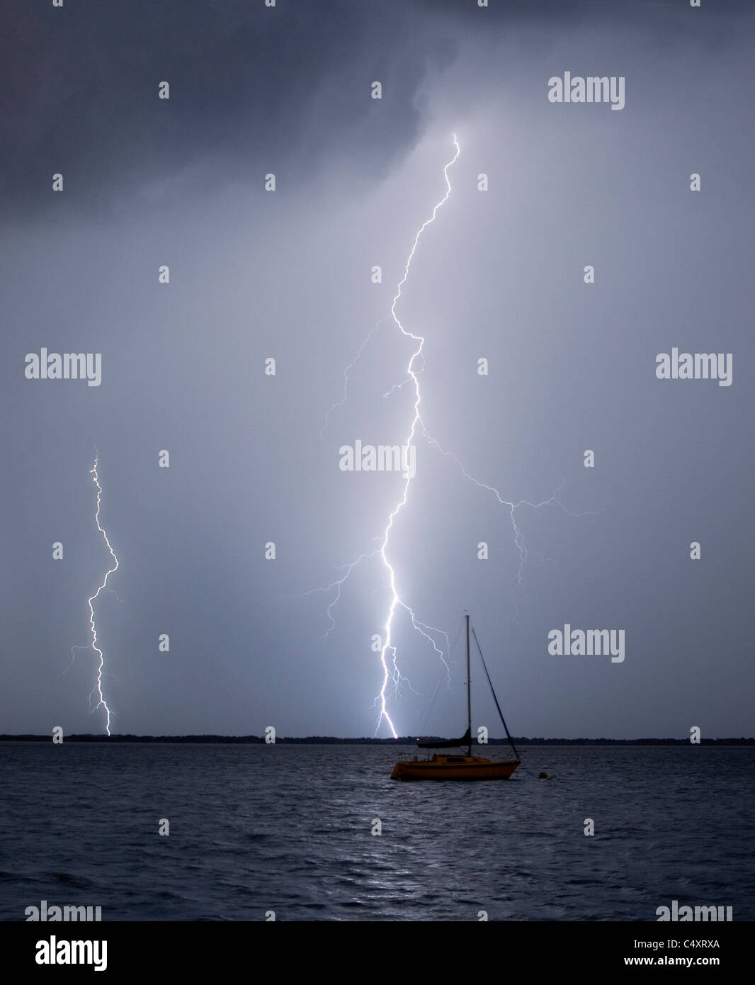 Ein Blitzeinschlag in der Nähe von einem festgemachten Segelboot Stockfoto