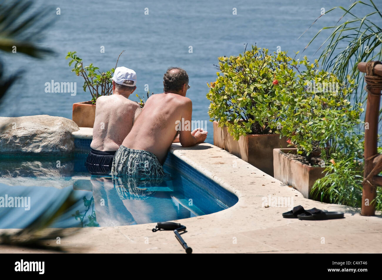 Ein senior männlichen Erwachsenen und älteren Vater entspannen Sie sich in einem Schwimmbad mit Blick auf den Pazifischen Ozean in San Pancho, Mexiko. Stockfoto
