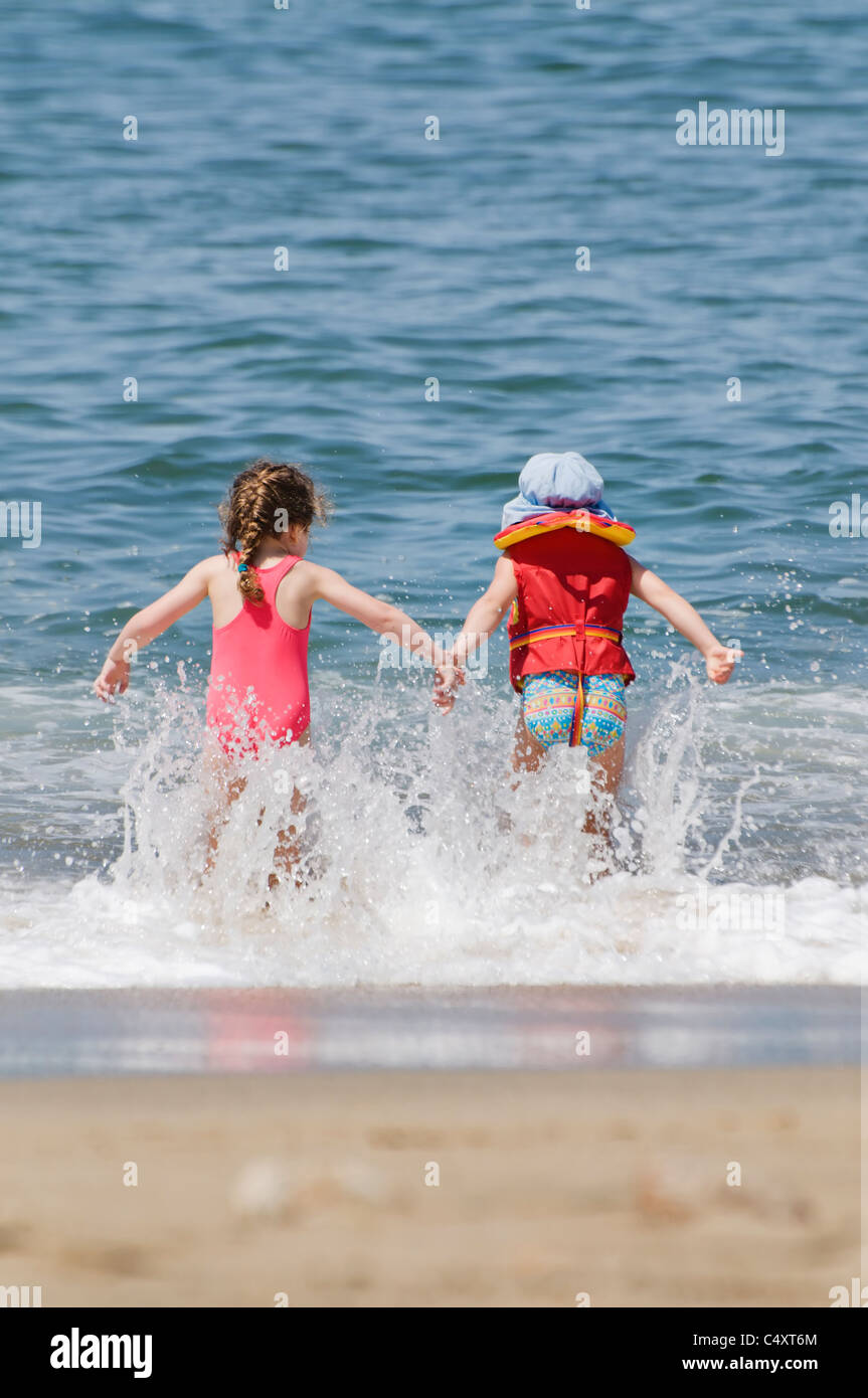 Zwei kleine Mädchen spielen in der Brandung am Strand in Sayulita, Nayarit, Mexiko. Stockfoto