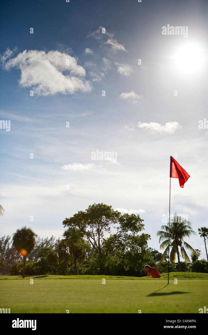 Golfspieler, die eine Aufnahme auf einem Golfplatz mit der Sonne brannte und ein paar Dutzend Wolken in den Himmel schweben Stockfoto