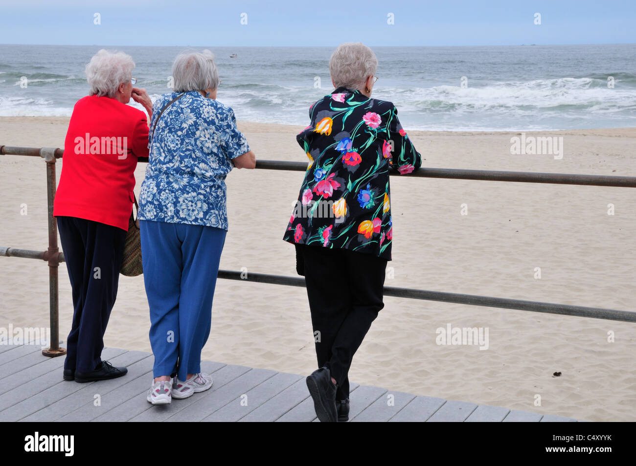 Bunte Frauen schauen Sie sich die Brandung in Spring Lake New Jersey. Diese Senioren finden einen bequemen Platz entlang der Promenade Stockfoto