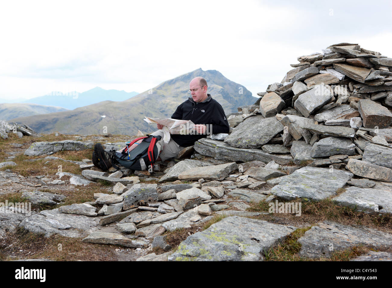 Mann, Blick auf eine Karte auf dem Gipfel des Ben Oss mit Ben Lui im Hintergrund Stockfoto