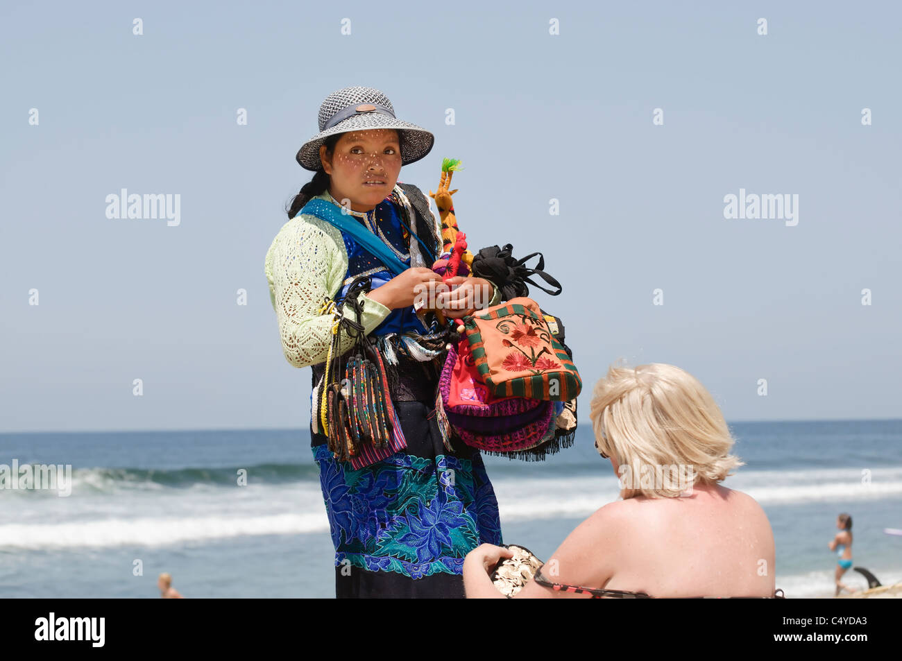 Eine Frau Strand Verkäufer zeigt ihre Ware an einem Touristen am Strand in Sayulita, Nayarit, Mexiko. Stockfoto