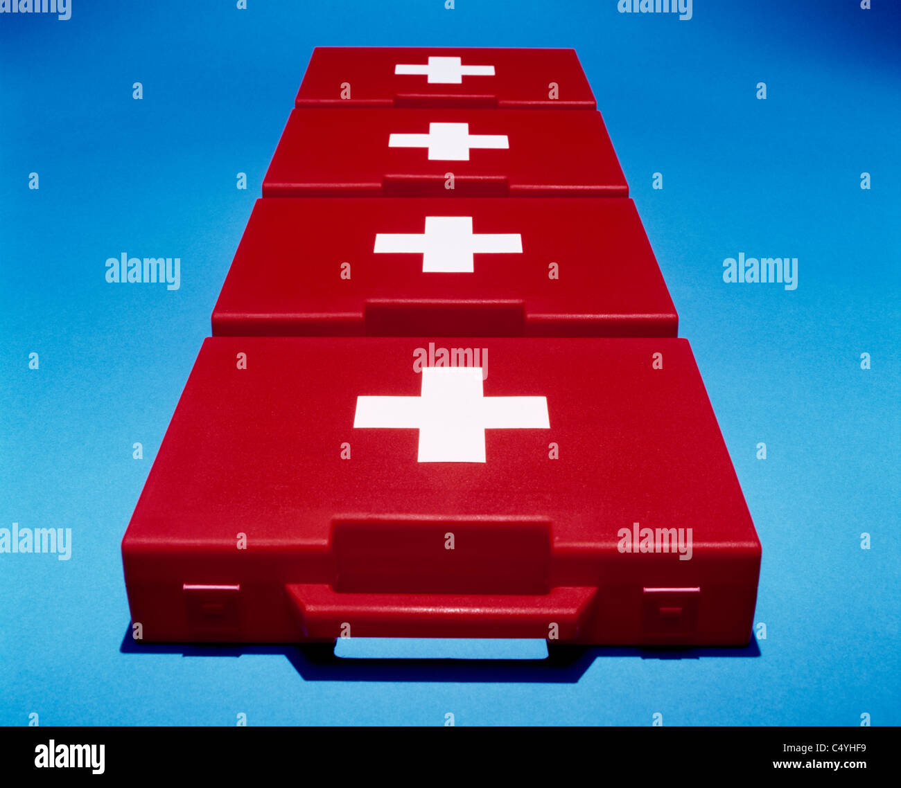 Vier helle rote erste Hilfe medizinische Boxen auf blauem Hintergrund Stockfoto