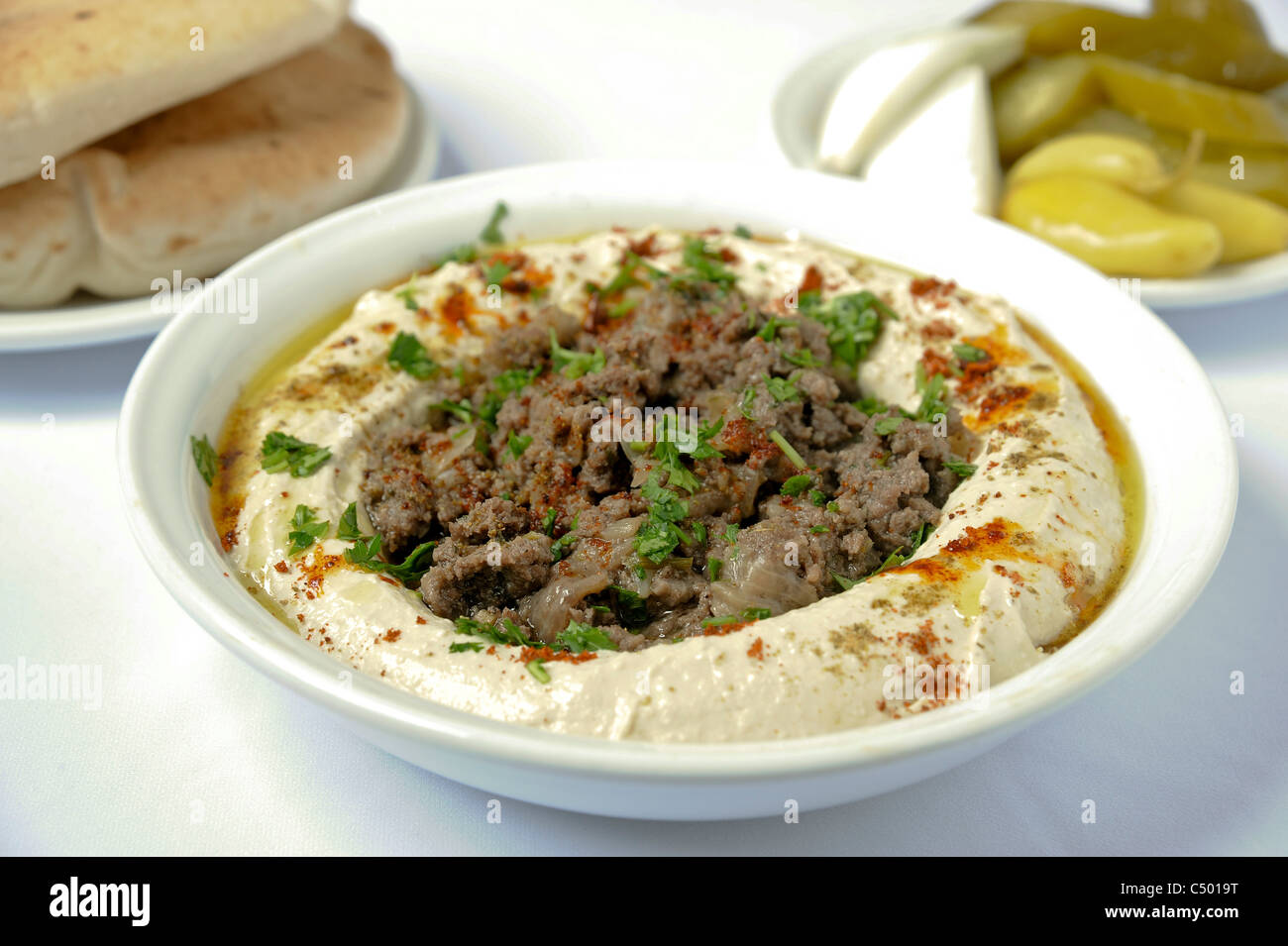 Hummus und Lamm mit Pitta und Gurken serviert Stockfoto