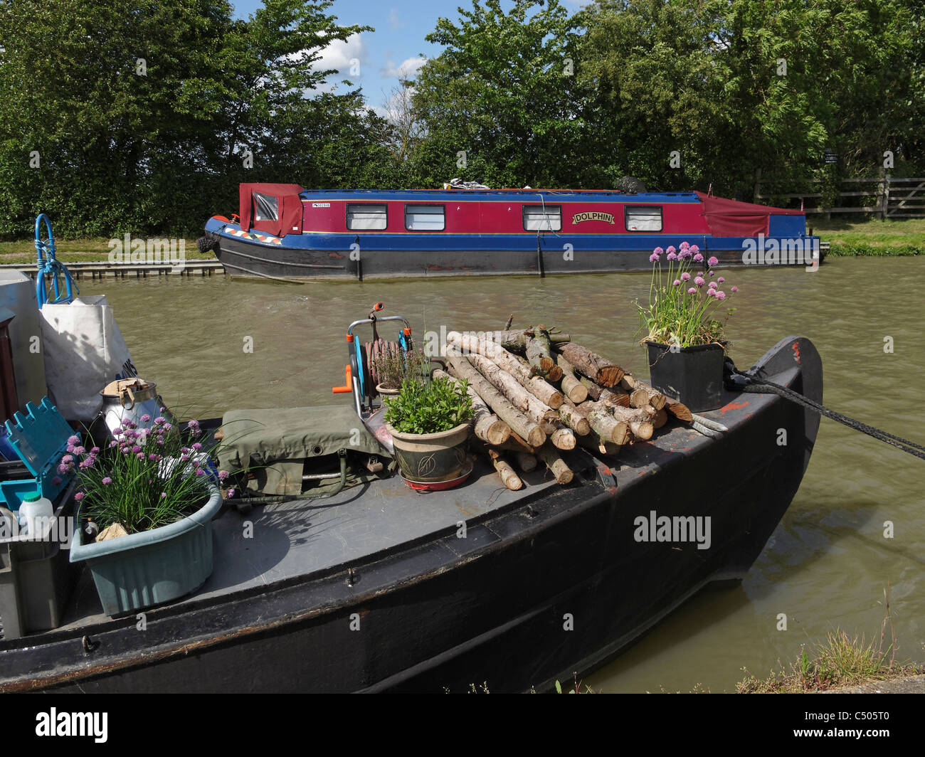 Pflanzen und Holz auf dem Bogen eine englische Narrowboat. Grand Union Canal, Northamptonshire, England. Stockfoto