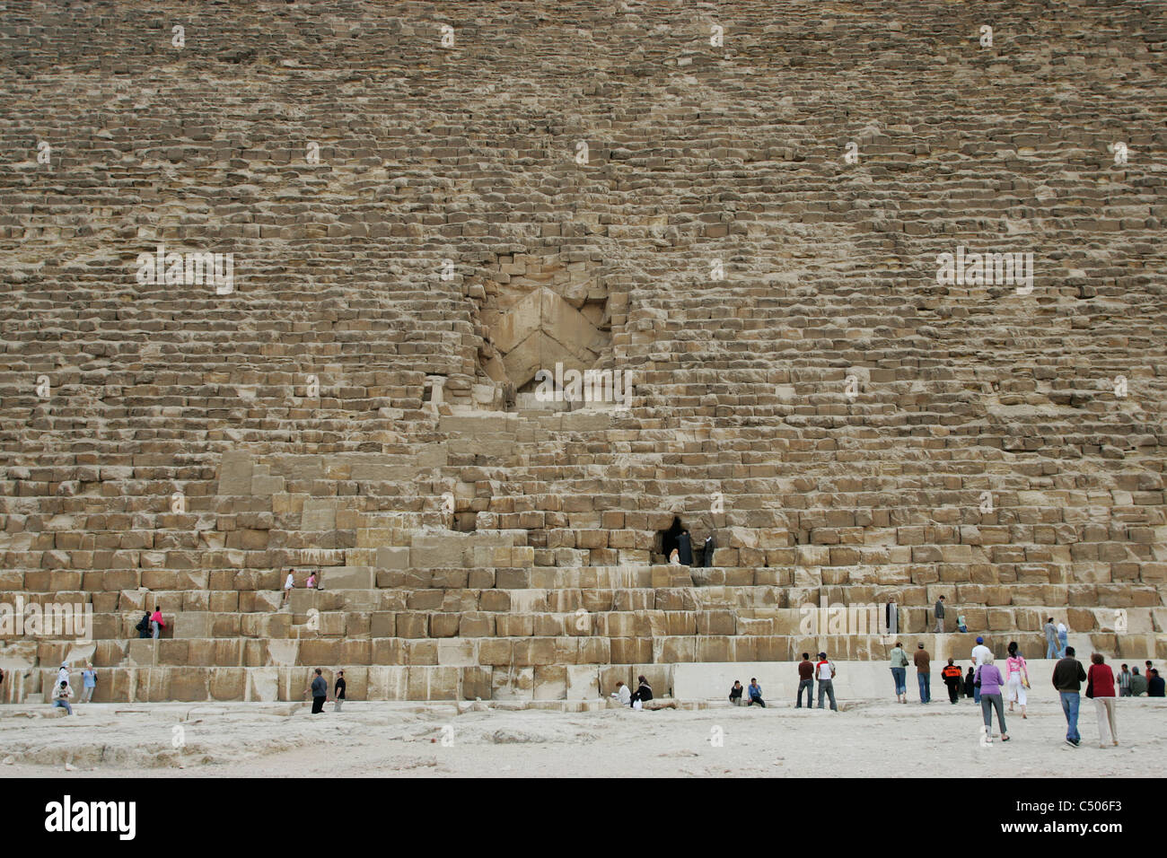 Touristen stehen an der Basis der großen Pyramide von Khufu, unten der Eingang zur Königskammer in Gizeh, Kairo, Ägypten Stockfoto