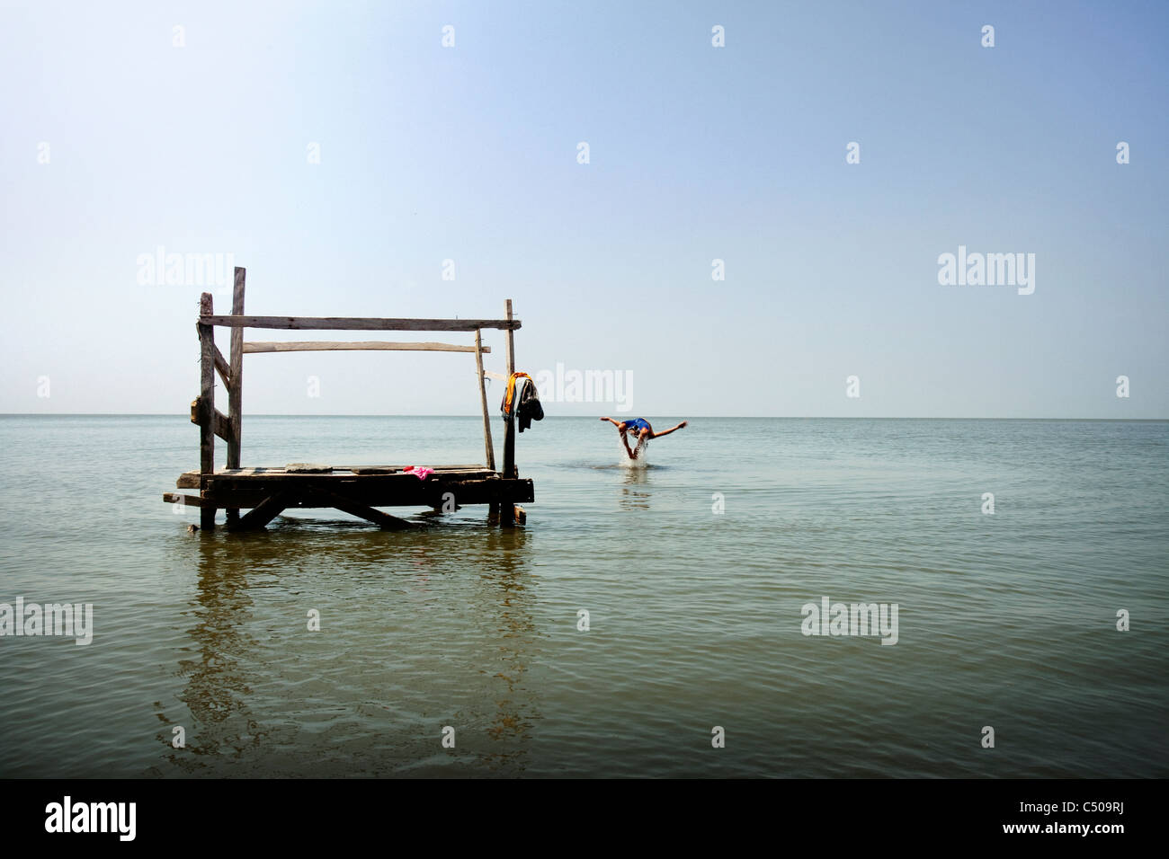 Person, die vom Pier ins Meer springen Stockfoto