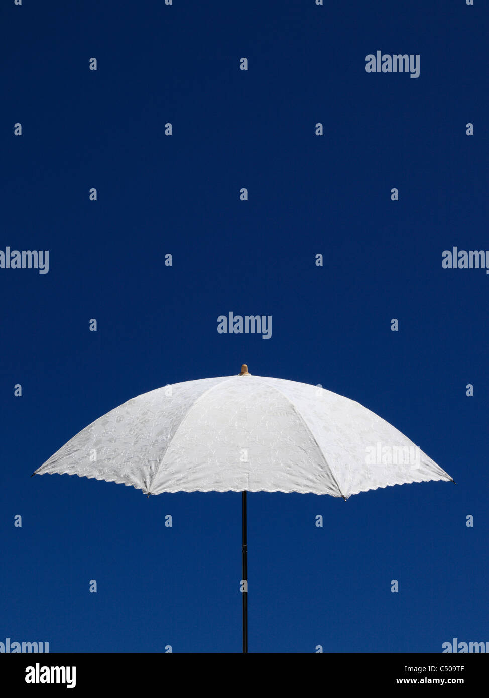 Ein Hand gehaltenen weißen Leinen Sonnenschirm mit gestickten Details, legen Sie gegen einen klaren, blauen Sommerhimmel. (Querformat Ref C509TX) Stockfoto