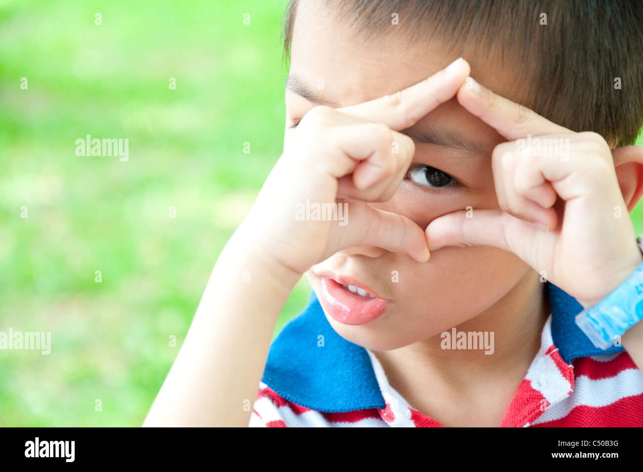 Junge blickt durch einen Rahmen aus Händen Stockfoto