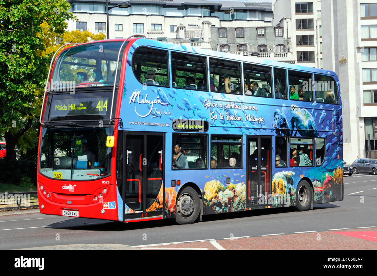 Werbung an der Seite des Doppeldeckerbusses, die den Tourismus in Malaysia mit farbenfrohen Werbespots in roter Farbe auf der Vorderseite des Busses in England UK fördert Stockfoto